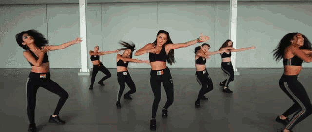 a group of women are dancing in a room and one of them is wearing a crop top that says ' rc '