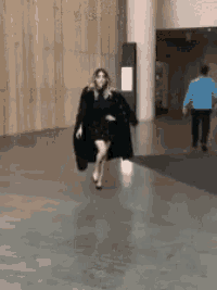 a woman in a black dress and fur coat is running
