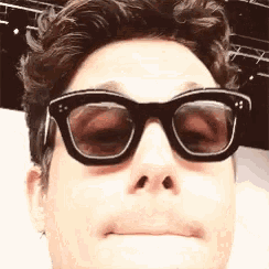 a close up of a man wearing sunglasses and making a funny face
