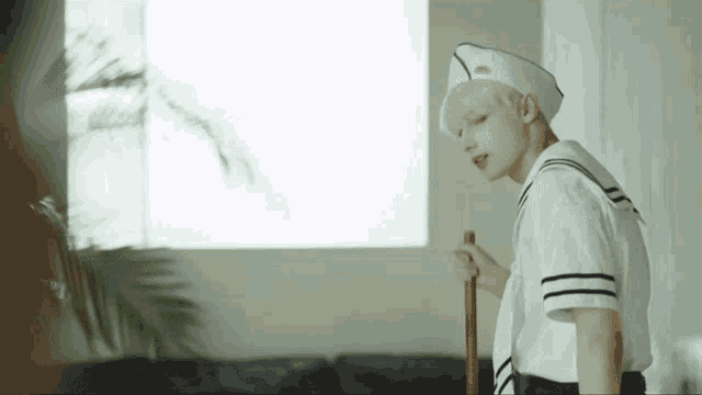 a man in a sailor 's uniform is holding a cane in a living room .