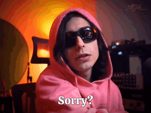 a man wearing sunglasses and a pink hoodie is saying sorry