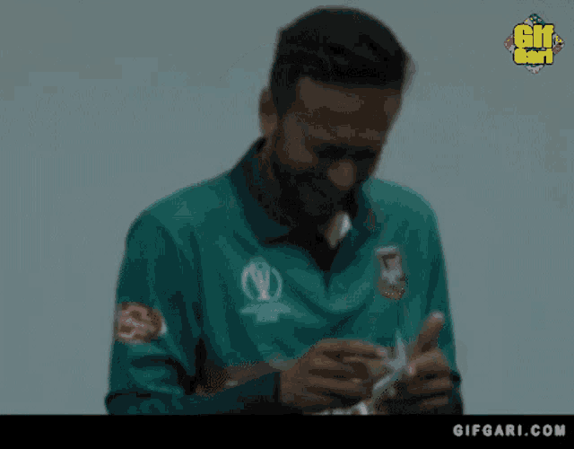 a man in a green shirt is smiling while holding a card in his hand .