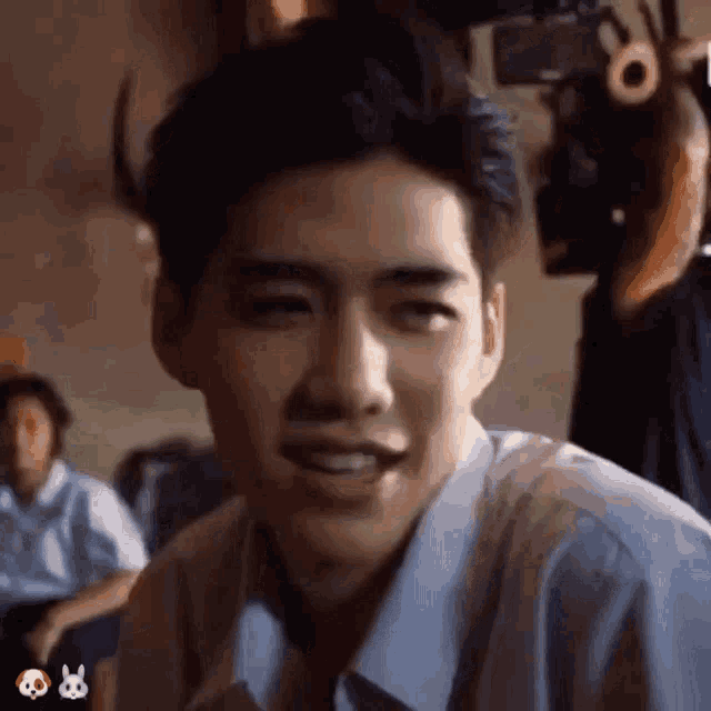 a young man in a blue shirt is making a funny face while sitting in front of a camera .