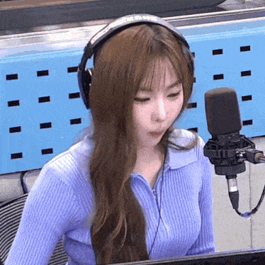 a woman wearing headphones is sitting in front of a microphone in a studio .