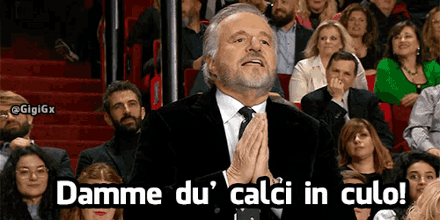 a man in a suit and tie is praying in front of a crowd with the words damme du calci in culo