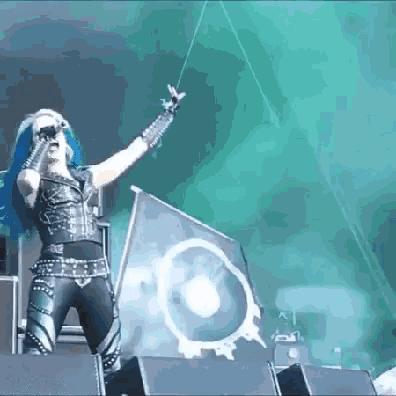 a woman with blue hair singing into a microphone on a stage