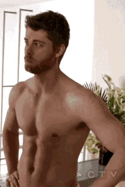 a shirtless man with a beard and mustache is standing with his hands on his hips .