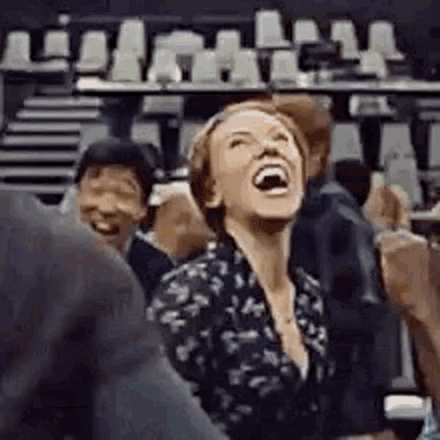 a woman is laughing in a crowd of people at a basketball game .
