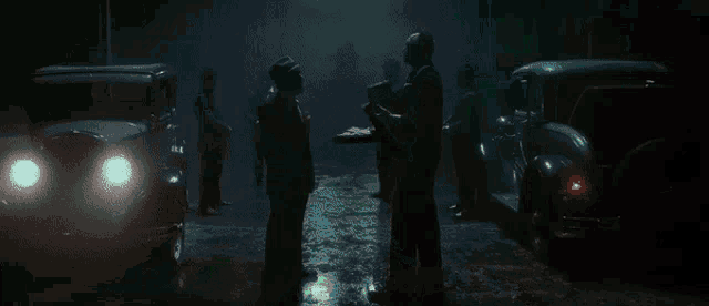 a group of men are standing in a dark room with a green light behind them