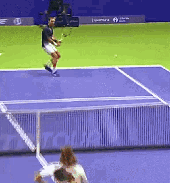 a man is jumping in the air while holding a tennis racket on a tennis court