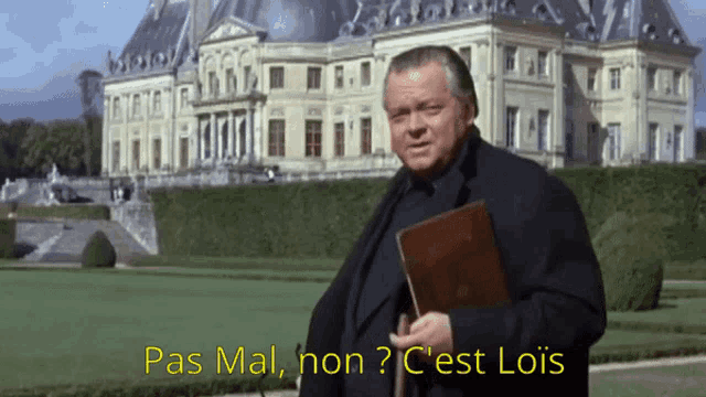 a man standing in front of a large building with the words pas mal non ? c est lois