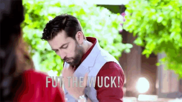 a man with a beard is standing next to a woman in a red shirt and holding her hand .