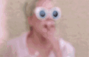 a woman wearing sunglasses and a flower in her hair is blowing a kiss .
