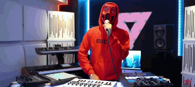 a man wearing a red hoodie that says sc on it is singing into a microphone