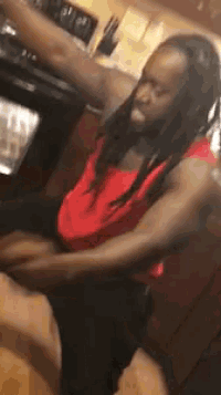 a man in a red shirt is sitting on a kitchen counter with his arms outstretched .
