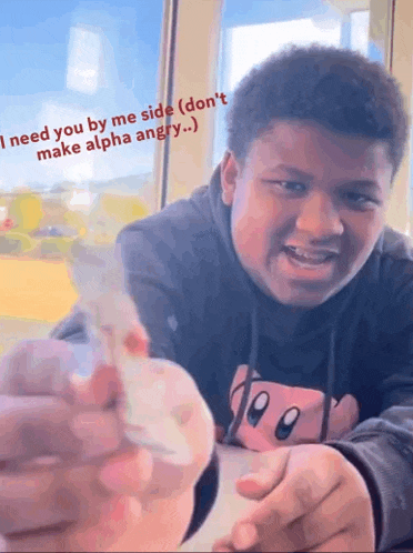 a young man is sitting at a table holding a piece of paper that says `` i need you by me side ''