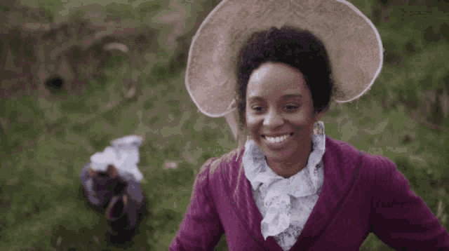 a woman wearing a large hat and a purple jacket is smiling