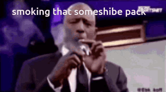 a man in a suit and tie is smoking a cigarette in front of a microphone while talking into it .