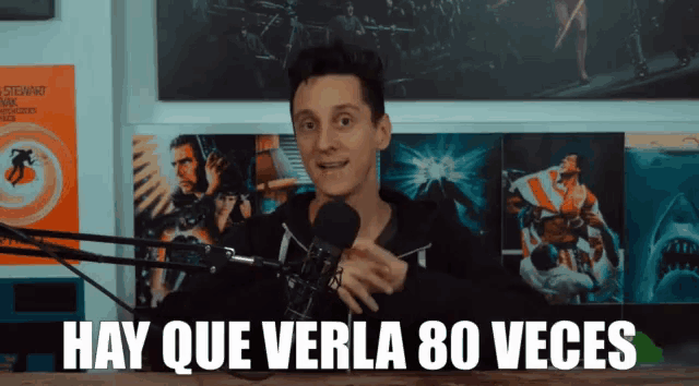 a man stands in front of a microphone with hay que verla 80 veces written on the bottom