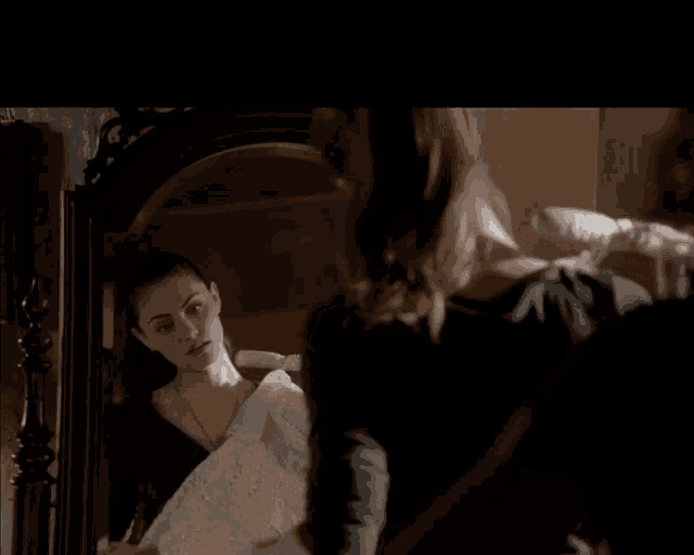 a woman is looking at herself in a mirror while holding a white cloth