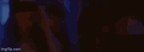 a woman is looking at the camera in a dark room .