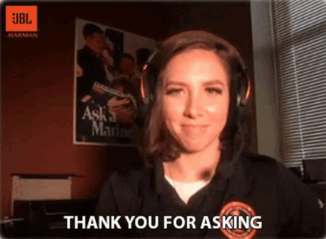 a woman wearing headphones says thank you for asking in front of an jbl harman poster