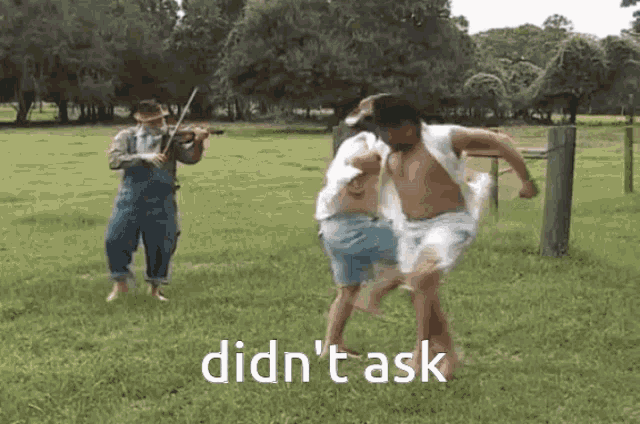 a man is playing a violin in a field while another man is dancing in a field .
