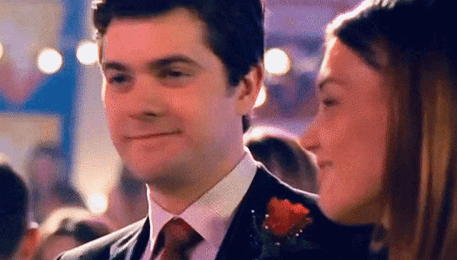 a man in a suit and tie is smiling at a woman in a crowd .