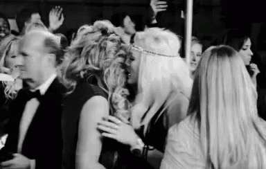 a black and white photo of two women hugging each other in a crowd of people .