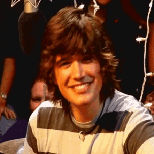 a young man wearing a striped shirt smiles for the camera