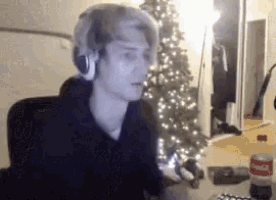 a man wearing headphones is sitting in front of a christmas tree in a room .