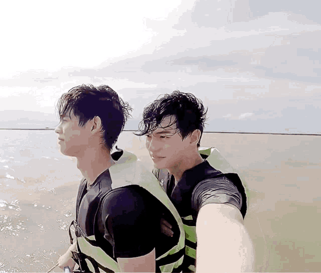 two men wearing life vests are taking a picture of themselves