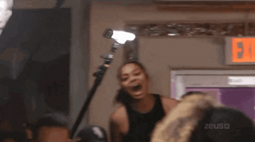 a woman is screaming in front of a camera while standing in front of a microphone .