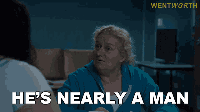 a woman talking to another woman with the words he 's nearly a man above her