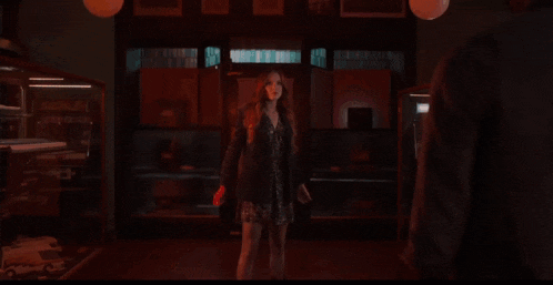 a woman is standing in front of a wall of fire