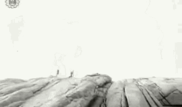 a black and white photo of a woman in a white swimsuit standing on a rocky beach .
