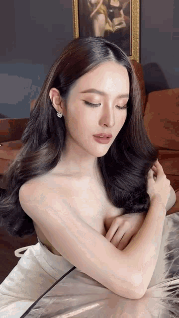 a woman in a white dress is sitting at a table with her eyes closed .