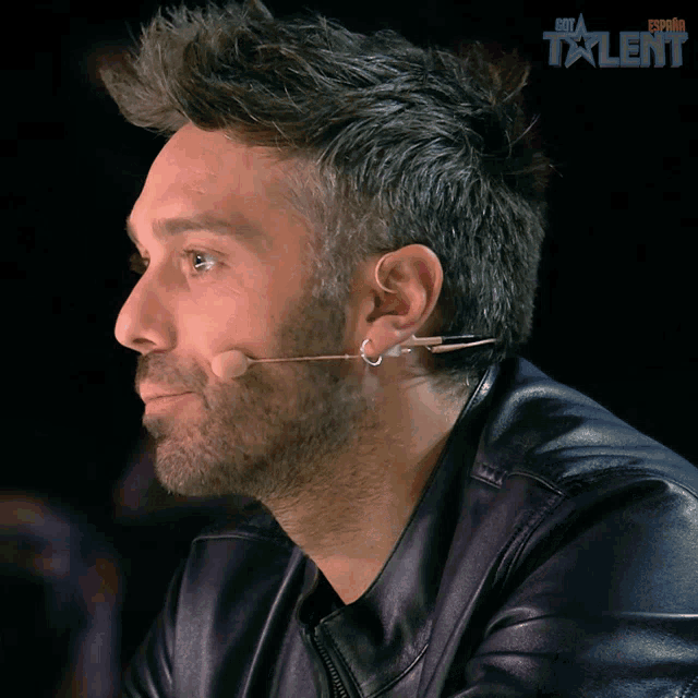 a man wearing a leather jacket and a microphone with the word talent on the bottom