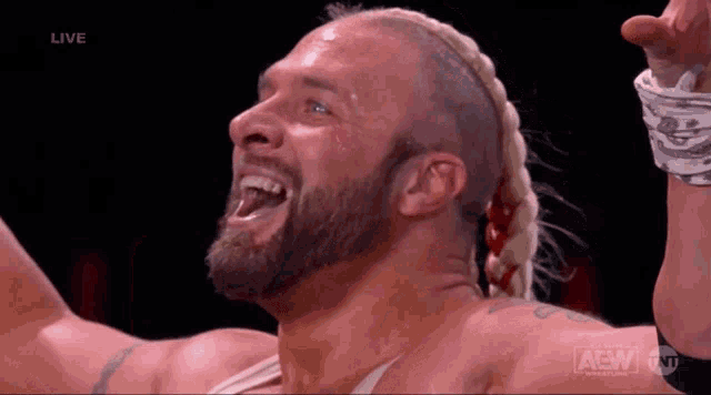 a wrestler with a braided hair and a beard is on a live aew tv show