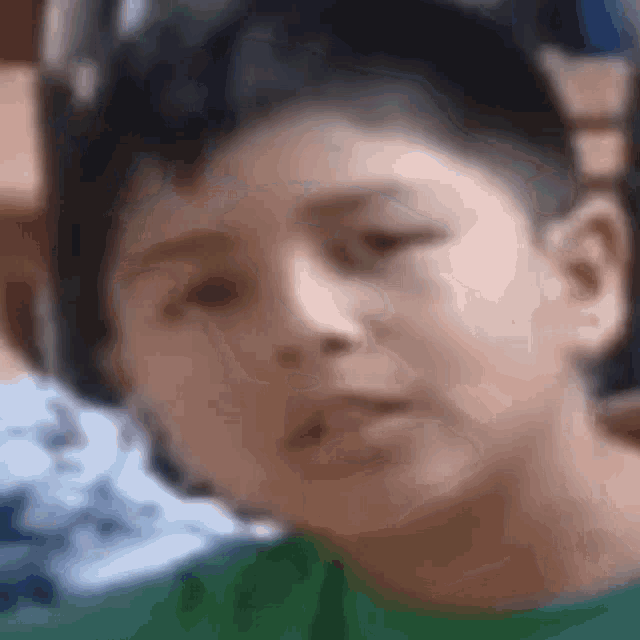 a close up of a young boy 's face with a green shirt on .