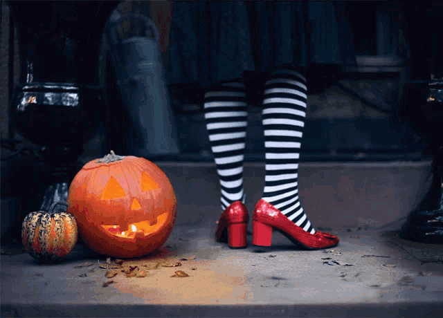 a woman wearing striped socks and red heels stands next to a carved pumpkin