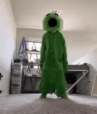 a person in a green frog costume is standing on the floor