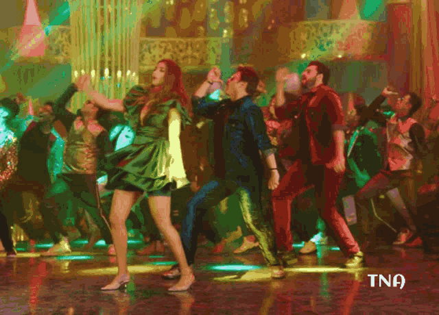 a woman in a green dress is dancing with a man