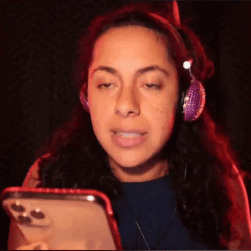 a woman wearing headphones is looking at her cell phone