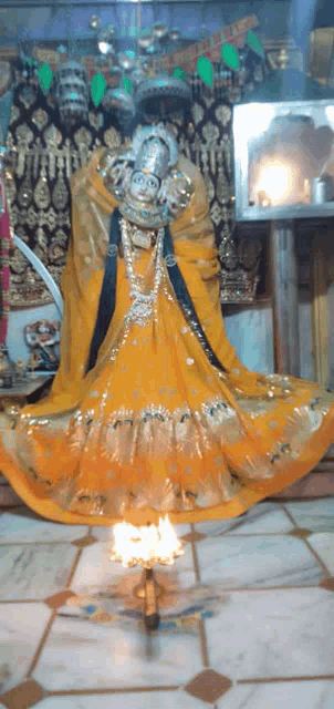 a statue of a woman in a yellow dress is standing in a temple