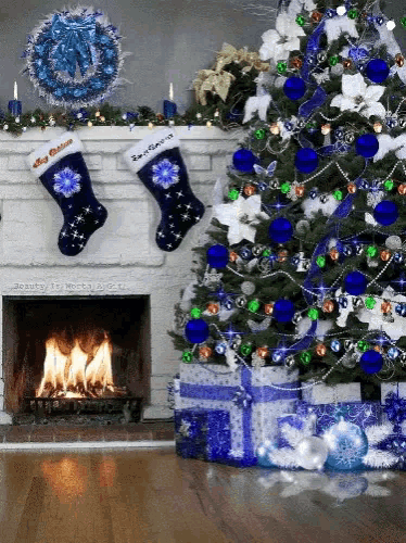 a christmas tree with blue and green decorations and a fireplace with two stockings hanging from it