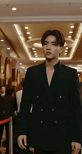 a man in a black suit is standing in a room
