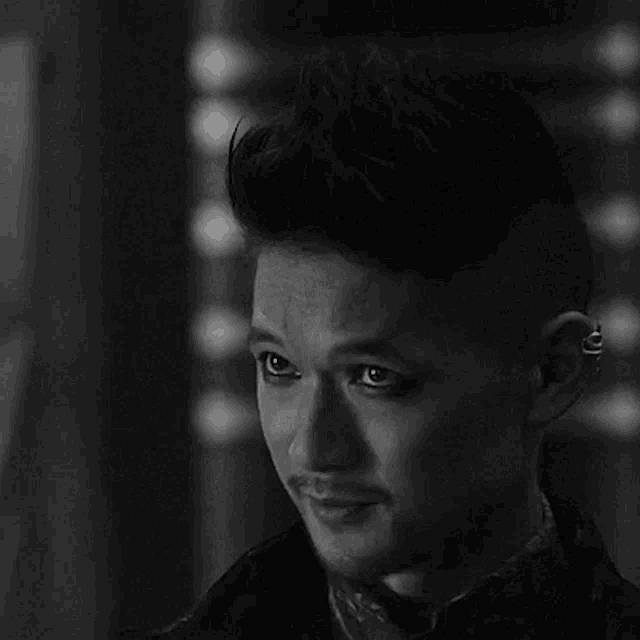 a black and white photo of a man with a piercing in his ear and a mohawk .