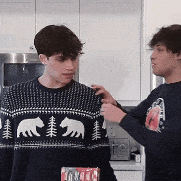a man in a sweater with bears and trees on it is being touched by another man .