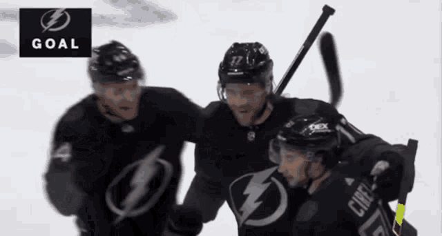 three hockey players celebrate a goal with a lightning bolt on their jerseys